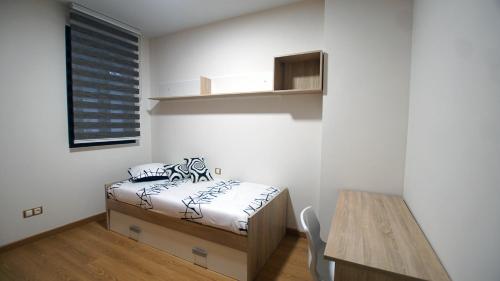 a small bedroom with a bed and a table at Apartamento con garaje, El barco in Toledo