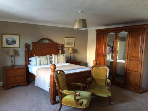 a bedroom with a large bed and two chairs at The Eagles Hotel in Llanrwst