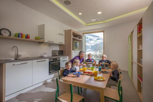 a group of children sitting at a table in a kitchen at Alpin Family Resort Seetal in Kaltenbach
