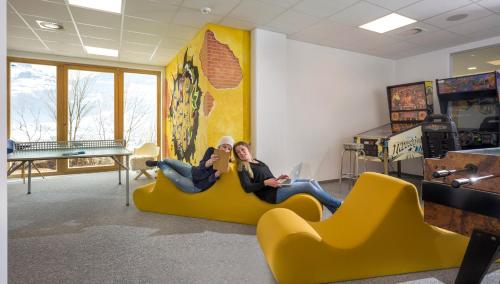 two people sitting on a yellow couch in a room at Alpin Family Resort Seetal in Kaltenbach