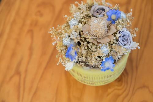 a yellow vase filled with blue flowers on a table at Troia Hotel in Amares