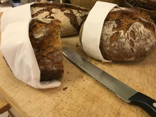 a loaf of bread on a cutting board with a knife at Familie Hopfeld - Hotel Dreikönigshof in Stockerau