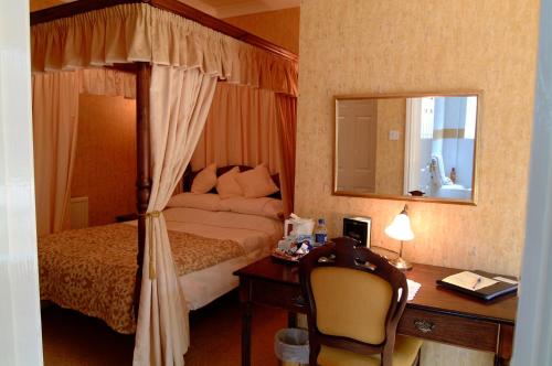 a hotel room with a bed and a desk with a desk at Rosedene Guest House in Pembroke