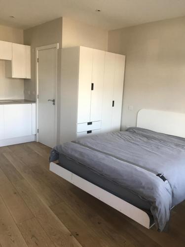 a bedroom with a large bed and white cabinets at The Annex in Ickenham