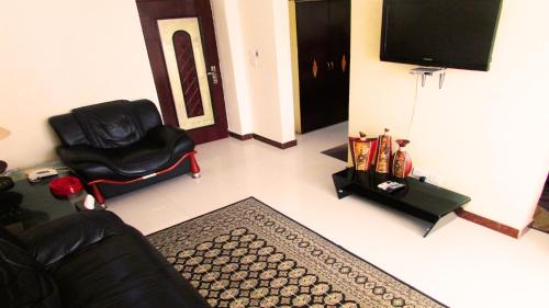 a living room with a black chair and a television at Urban Rose Hotel & Apartments in Dar es Salaam