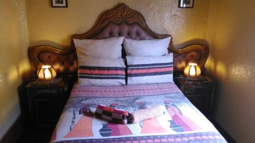 a bed with a wooden head board and two lamps at Authentic Bicycle Tours and Backpackers in Soweto