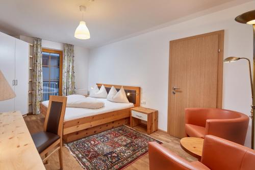 a bedroom with a bed and a table and a chair at Appartements am Stadtpark Zell am See in Zell am See