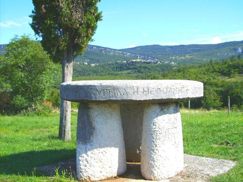 a stone bench sitting in a field with a tree at Holiday Home Deni in Roč