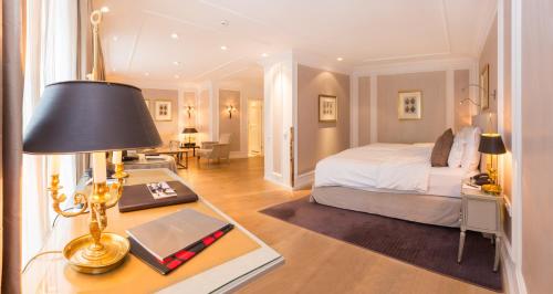 a bedroom with a bed and a desk with a lamp at Hotel München Palace in Munich