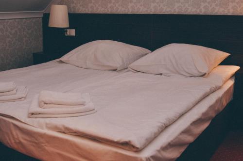 a large white bed with two pillows and two towels at Pyszna Stajenka in Bąków