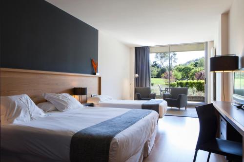 a hotel room with two beds and a desk and a room with at Hotel Món Sant Benet in Sant Fruitos de Bages