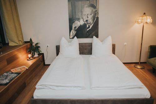 a white bed in a room with a portrait of a man at Projekt GASTRAUM in Illertissen