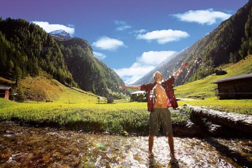 a man standing in a field with his arms outstretched at Hotel Krimmlerfälle in Krimml