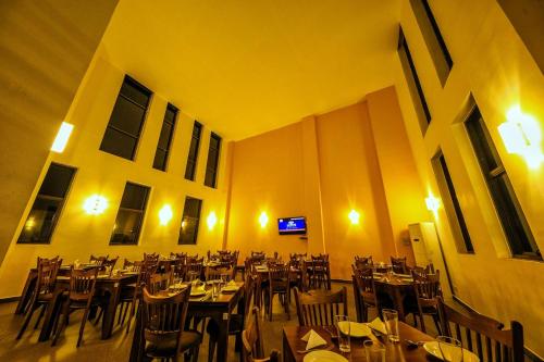a dining room with tables and chairs and a tv at Golden Pier City Hotel in Colombo