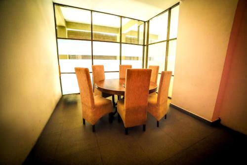 a dining room with a table and chairs and windows at Golden Pier City Hotel in Colombo