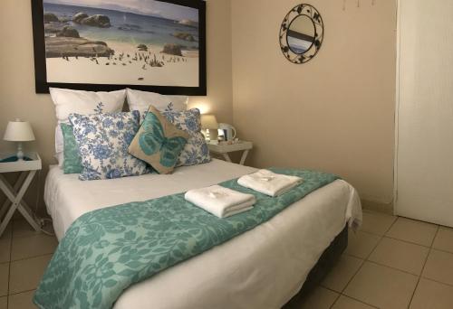 a bedroom with a bed with two towels on it at Bay Breeze Guesthouse Selfcatering in Gordonʼs Bay