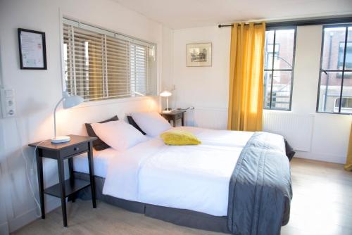 a bedroom with a large white bed and a window at Hotel et le Cafe de Paris in Apeldoorn