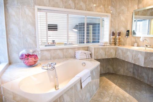 a bathroom with a tub and a sink and a window at Hotel et le Cafe de Paris in Apeldoorn