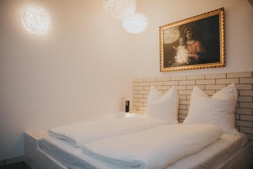 a bedroom with a bed with white pillows and a painting at Projekt GASTRAUM in Illertissen