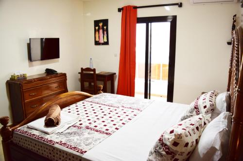 ein Schlafzimmer mit einem Bett, einer Kommode und einem Fernseher in der Unterkunft Kakatar Family Residence , Yoff in Dakar