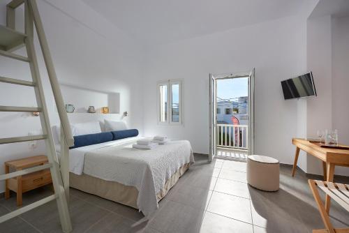 a white bedroom with a bed and a balcony at Pagona Studios in Pollonia