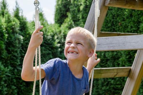 a young boy swinging on a rope swing at Kärnten Apartment Turnersee in Sankt Kanzian