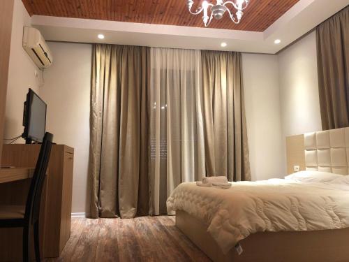 a bedroom with a bed and a tv and curtains at Hotel Lungomare in Vlorë