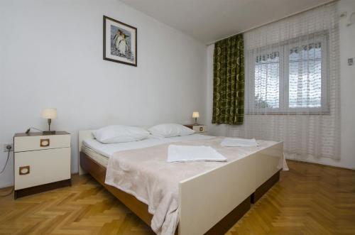 a white bedroom with a bed and a window at Apartments Anka 20m from the beach in Duće