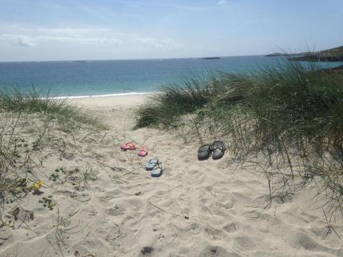 a pair of shoes sitting on the sand on a beach at Beachcomber Cottages in Ballyconneely