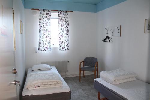 a room with two beds and a window and a chair at Trosa Vandrarhem in Trosa