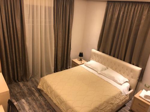 a bedroom with a white bed and curtains at Hotel Lungomare in Vlorë