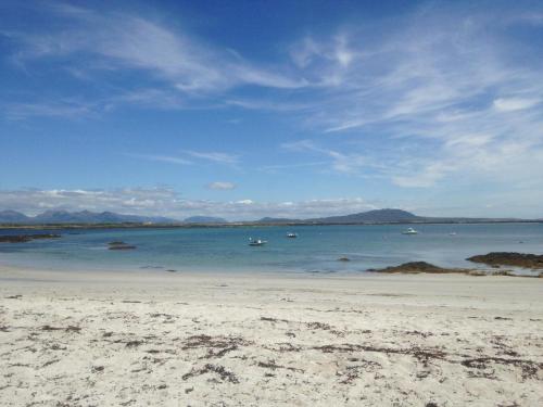 a sandy beach with boats in the water at Beachcomber Cottages in Ballyconneely