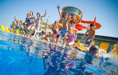 a group of children jumping into a swimming pool at All in Red Thermenhotel in Lutzmannsburg