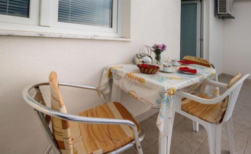 a table with two chairs and a table with flowers on it at Apartments Igor in Krvavica