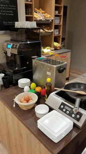 a kitchen with a counter top with eggs in a basket at The Originals Boutique, Hôtel La Chaussairie, Rennes Sud in Chartres-de-Bretagne