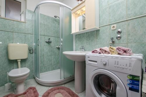 a bathroom with a washing machine and a sink at Apartments Nada in Postira