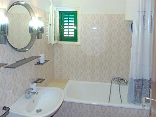 a bathroom with a sink and a bath tub and a mirror at Apartments Frano in Postira