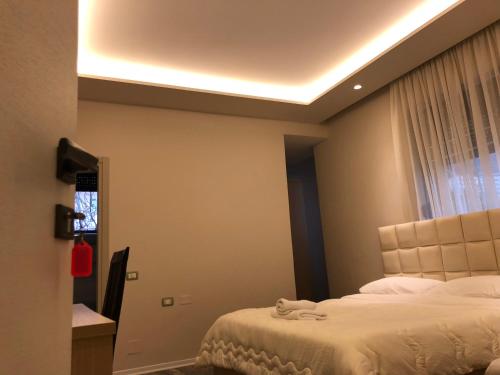 a bedroom with a bed and a window and a ceiling at Hotel Lungomare in Vlorë