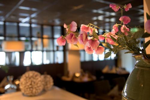 a vase filled with pink flowers on a table at Hotel et le Cafe de Paris in Apeldoorn