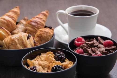 a table with three bowls of pastries and a cup of coffee at Maximus Hotel Byblos in Jbeil