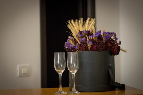 ヤシにあるRent Room N&Sのワイングラス2杯、テーブルの上に飾られた花のバケツ