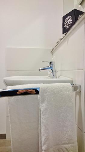 a bathroom with a sink and towels on a shelf at Gästehaus Langhammer in Bubenreuth