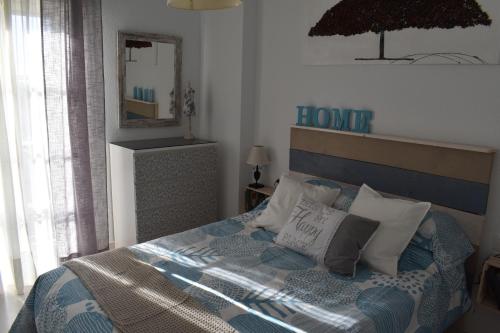 トレモリノスにあるResidencial Campomanesのベッドルーム1室(青いヘッドボードと鏡付きのベッド1台付)