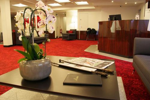 a lobby with a table with a vase of flowers on it at Hotel Le Richemont in Paris