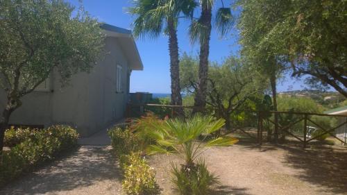 a house with palm trees and a fence and a yard at La scogliera del capo in Santa Maria
