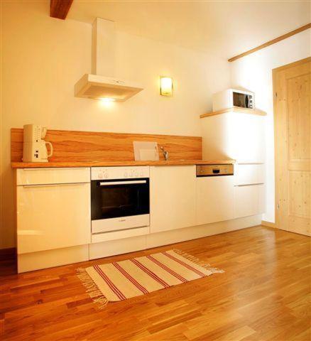 a kitchen with white appliances and a wooden floor at Appartement Seeland in Weissensee