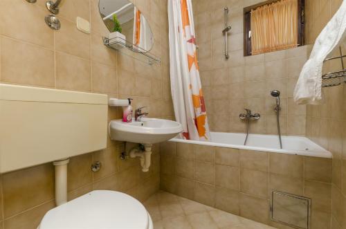 Un baño con inodoro, lavabo y bañera. en Apartments Denis, en Supetar