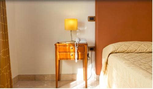 a table with a lamp on it next to a bed at Ranch Palace Hotel in Naples