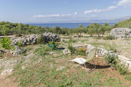 a white chair sitting in a field next to a rock wall at House Lucica in Splitska