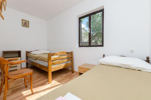 a bedroom with two beds and a desk and a window at Apartment Barba in Rogač